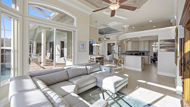 A spacious living area with a large sectional sofa, a glass coffee table, and a ceiling fan. - Pet-friendly Waterfront Home With Heated Pool and spa (Marco Island)
