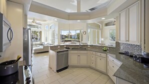 A spacious kitchen with a large island, white cabinetry, and a dishwasher. - Pet-friendly Waterfront Home With Heated Pool and spa (Marco Island)