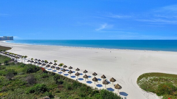 A beach with thatched umbrellas and a clear blue sky. - Sunny Beachfront Condo With Pool and Sw-facing Balcony (Marco Island)