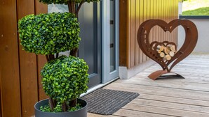 A wooden door with a heart-shaped metal decoration and a potted plant with a spherical topiary. - Schmitten Finest Apartment - SKYBLUE (Zell am See)