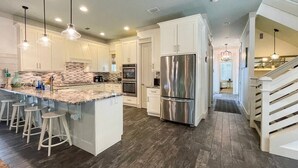 A spacious kitchen with a large island, stainless steel appliances, and a dark wood floor.