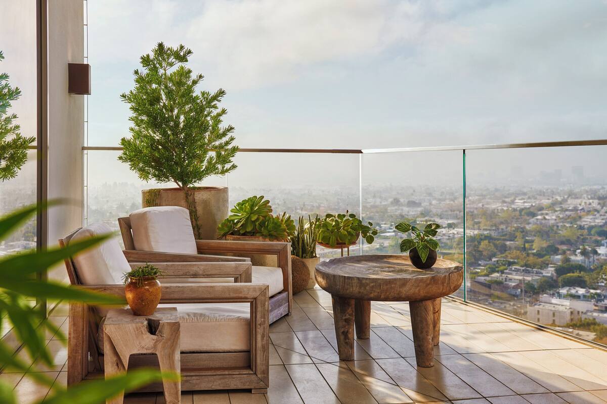 Un balcon agrémenté de meubles en bois, de plantes en pot et offrant une vue sur le paysage urbain.