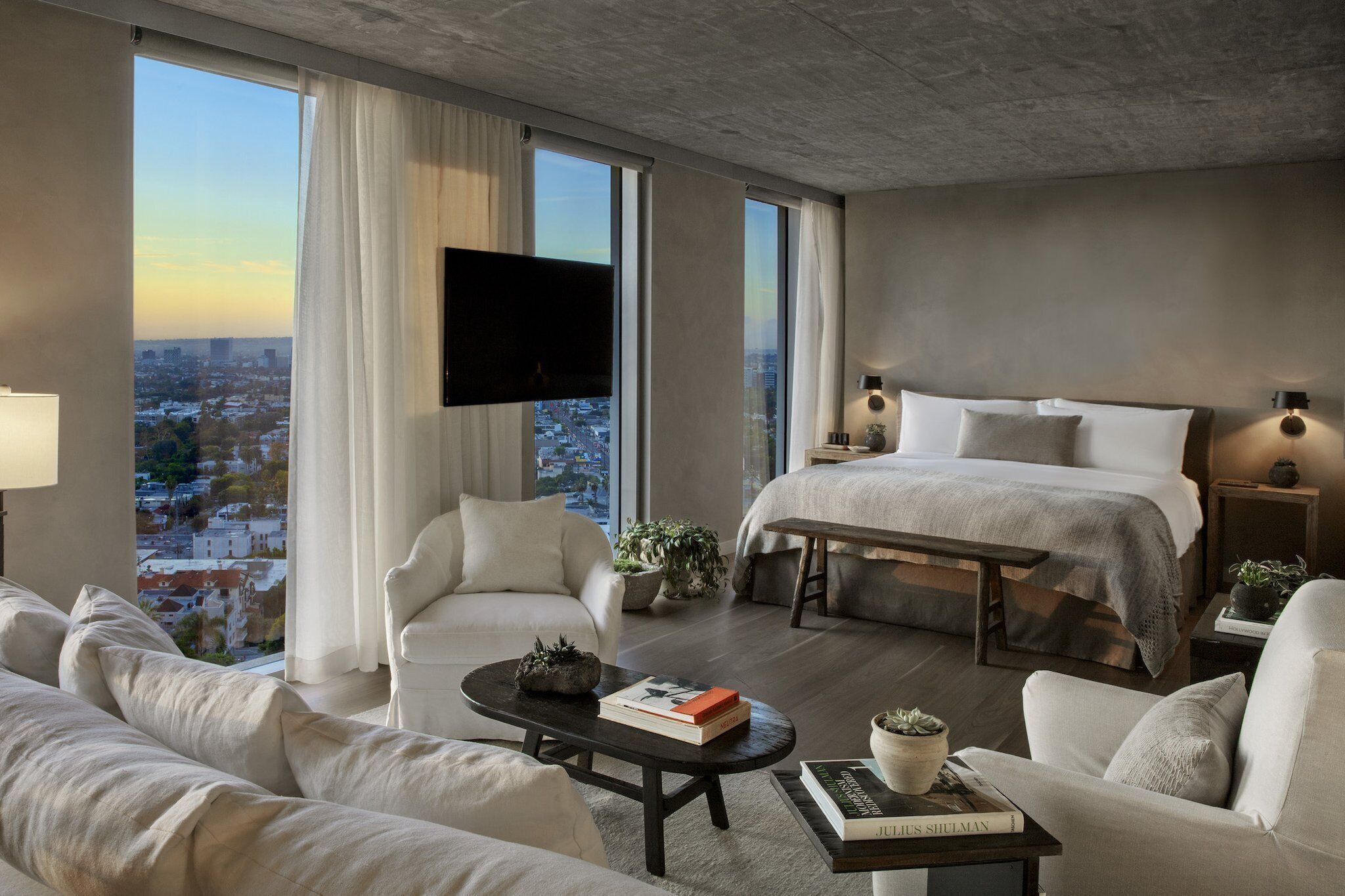 Una habitación de hotel moderna con una cama grande, un sofá, una mesita de centro y un televisor.