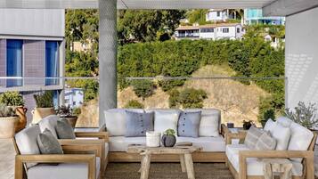 A modern outdoor seating area with a sofa and chairs, a wooden coffee table, and potted plants.