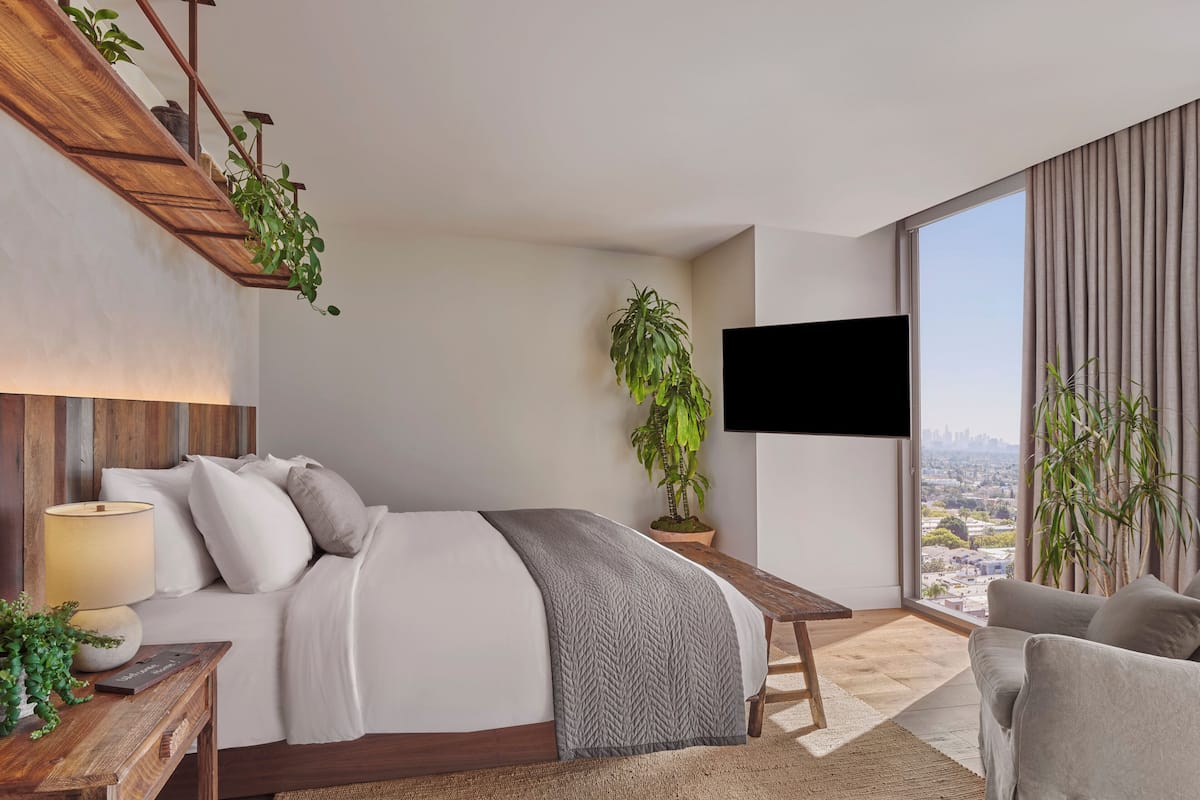 Une chambre d’hôtel moderne dotée d’un grand lit, d’un bureau, d’une télévision et offrant une vue sur la ville.