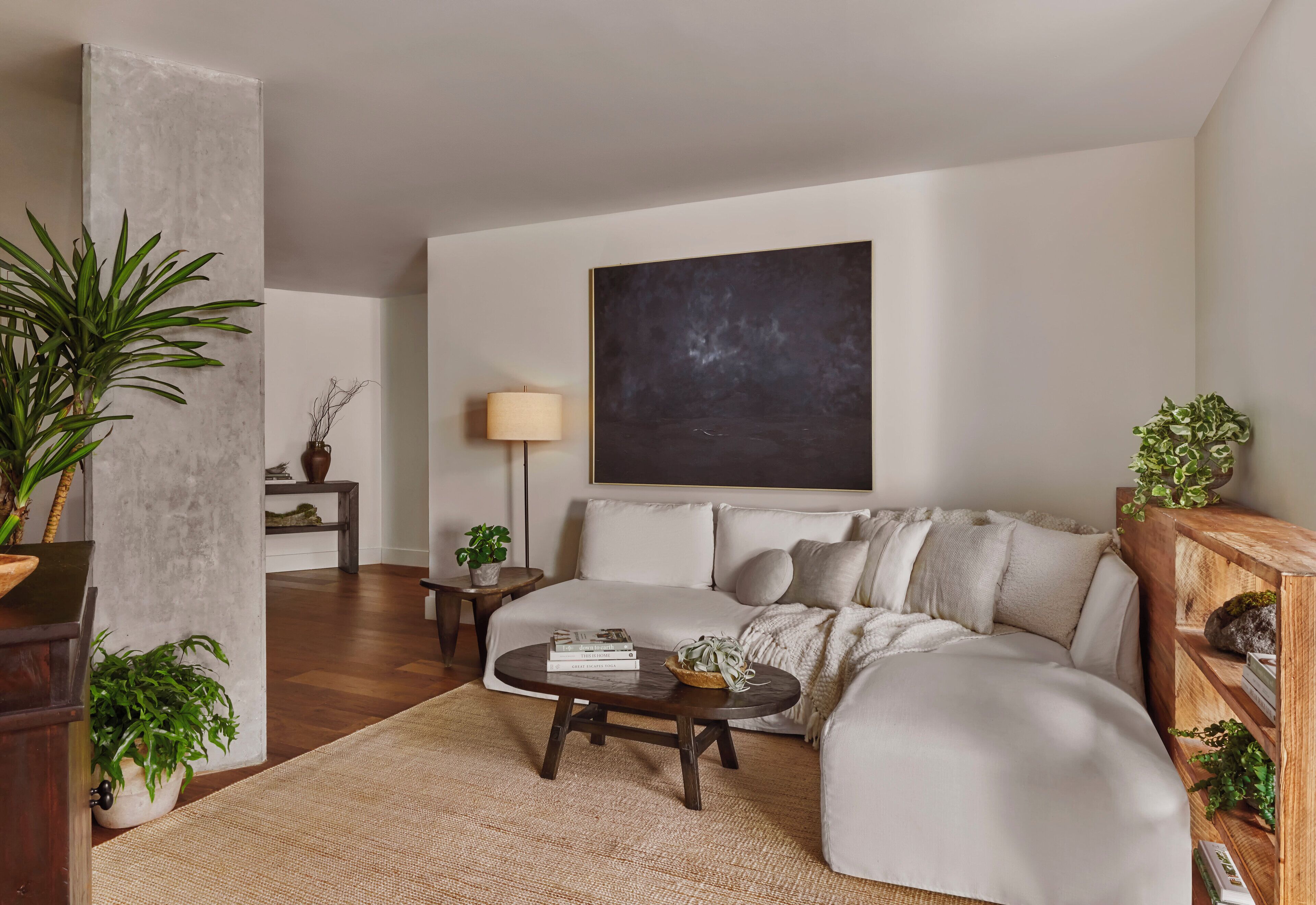 A modern living room with a sectional sofa, a round coffee table, and a large abstract painting on the wall.