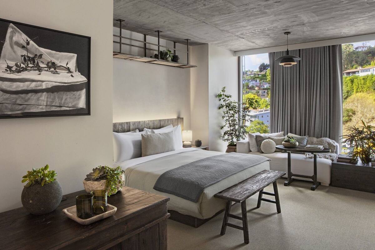 Une chambre d’hôtel moderne dotée d’un grand lit, d’un coin salon avec vue et d’une table à manger.