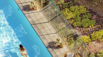 Una piscina al aire libre, sombrillas, sillones reclinables de piscina