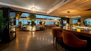 Ein geräumiges, modernes Restaurant mit hoher Decke, großen Fenstern und einer Bar.