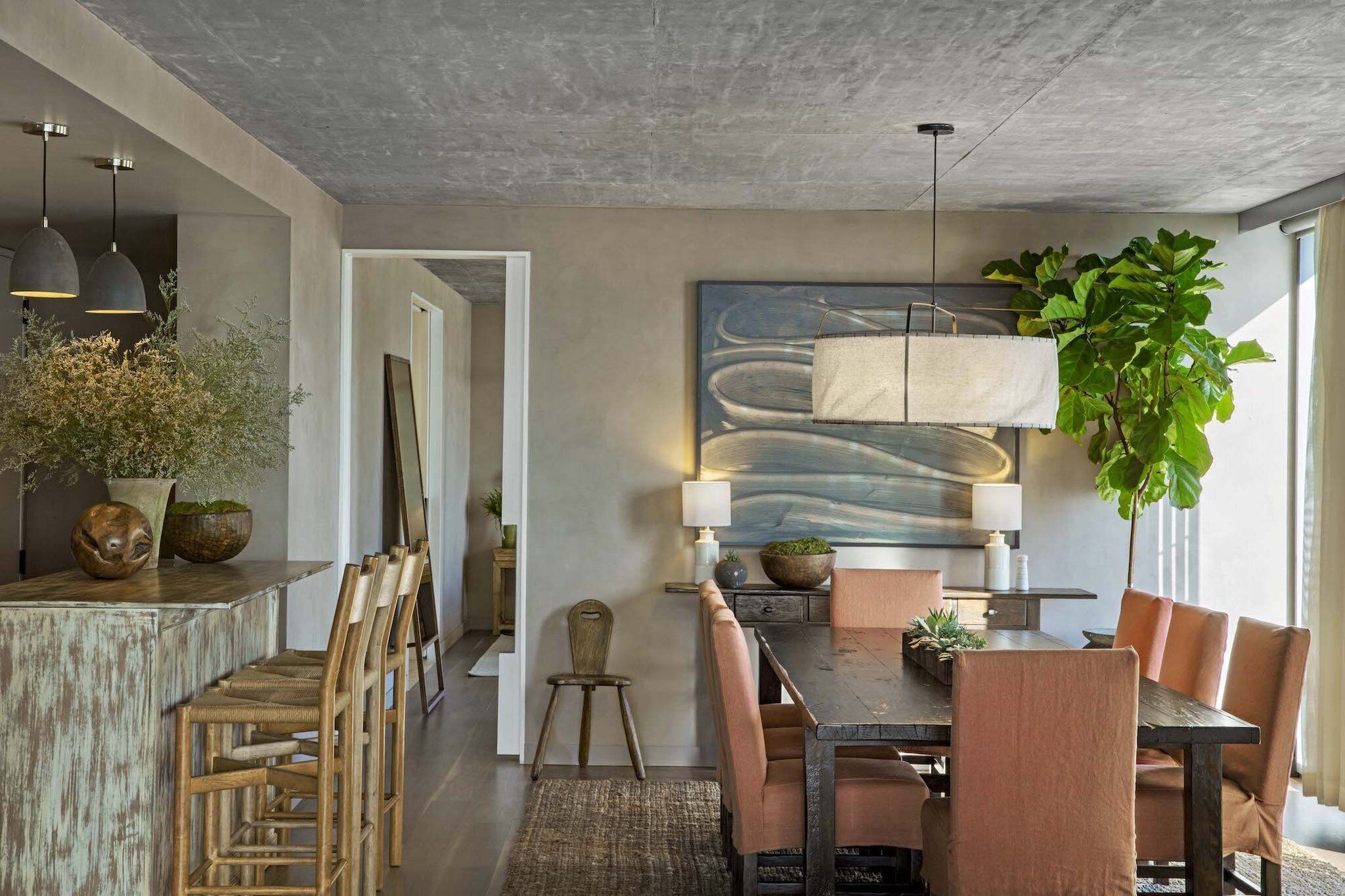 Un comedor moderno con una mesa de madera, sillas acolchadas e iluminación colgante.
