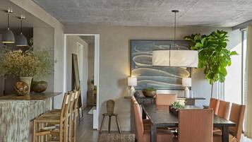 Un comedor moderno con una mesa de madera, sillas acolchadas e iluminación colgante.