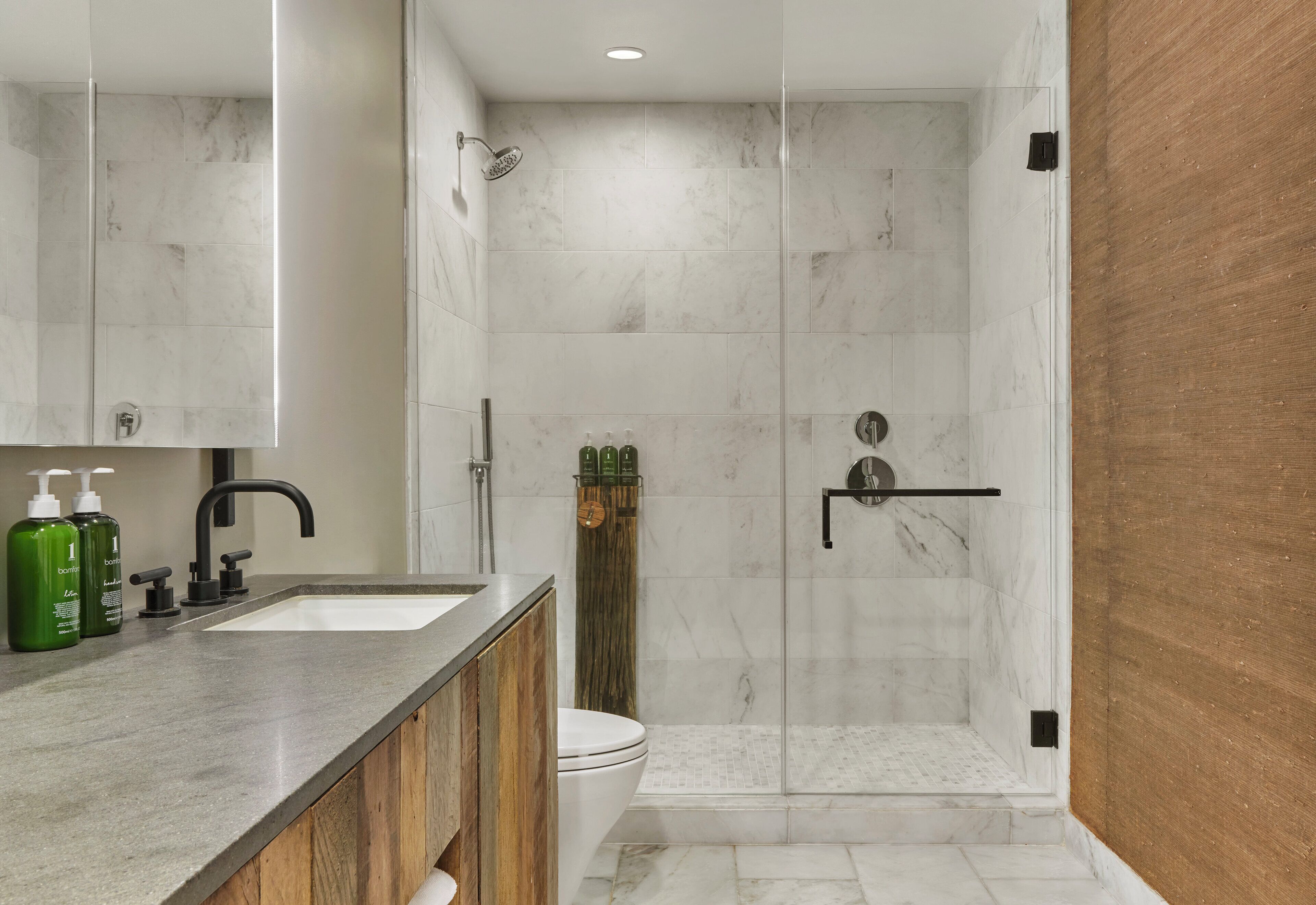 Une salle de bain moderne avec une douche en marbre, un lavabo avec un meuble-vasque en bois et des toilettes.