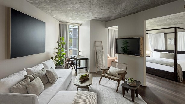Ein modernes Wohnzimmer mit einem großen Flachbildfernseher, einer Couch, einem Couchtisch und einer an der Wand stehenden Leiter.