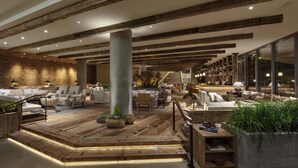 Eine großzügige Lobby mit Holzboden, modernen Sitzbereichen und einer zentralen Säule.
