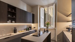 Una cocina moderna con armarios oscuros, una isla central y una ventana con contraventanas.