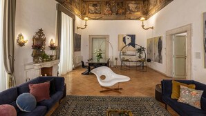 Un salón amplio con techo alto, detalles ornamentales en el techo y chimenea, además de muebles modernos.
