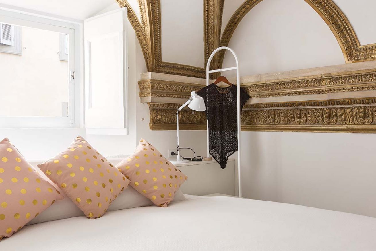 Une chambre à coucher comprenant un lit, une table de chevet, une lampe et un portant à vêtements suspendu.