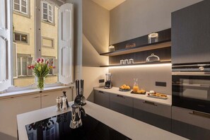 A modern kitchen with a central island, built-in appliances, and a window with a view of a building. - COSTAGUTI EXPERIENCE (Roma)