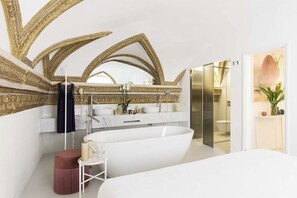 A modern bathroom with a freestanding bathtub, a vanity with a large mirror, and a shower area.