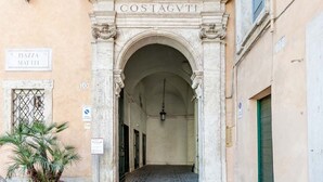 Una entrada con un arco y una placa que dice "COSTAGVTI" y otra que dice "R. PIAZZA MATTEI".