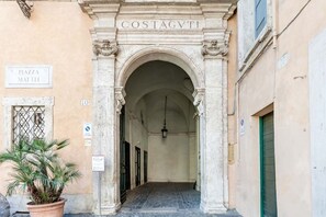 An entrance with an arched doorway labeled "COSTAGVTI" and a sign "R. PIAZZA MATTEI". - COSTAGUTI EXPERIENCE (Roma)
