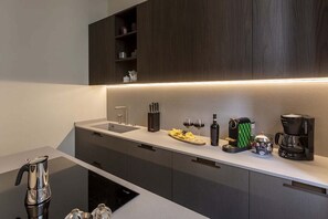 A modern kitchen with dark wood cabinets, a white countertop, and a built-in oven. - COSTAGUTI EXPERIENCE (Roma)