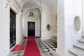 A hallway with a checkered floor, a red carpet, and a black door at the end. - COSTAGUTI EXPERIENCE (Roma)