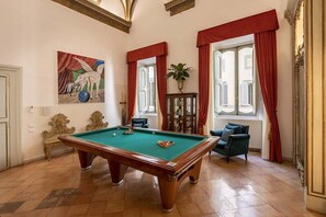 A room with a pool table, a painting, a plant, and a window with curtains. - COSTAGUTI EXPERIENCE (Roma)