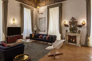 A living room with a sofa, television, fireplace, and decorative wall sconces. - COSTAGUTI EXPERIENCE (Roma)