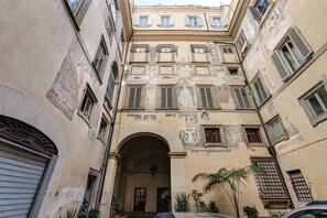 A narrow alleyway with a building featuring a central archway, multiple windows, and decorative elements.
