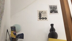 A staircase with a yellow handrail, a black vase on the landing, and a magazine rack with various publications. - The werewolf lair (Bléré)