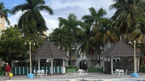 A pool area with lounge chairs and tables, surrounded by palm trees and a gazebo. - Cool's 1bd, Villa B6, On the Beach&Garden View WIFI (Ocho Rios)