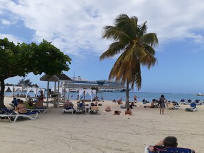 Na praia, espreguiçadeiras, toalhas de praia 
