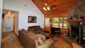 A cozy cabin interior with a stone fireplace, wooden ceiling, and a sofa set. - DAYBREAK LOG GETAWAY - NEW HOT TUB! (Murphy)