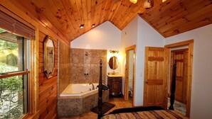 A wooden cabin bathroom with a stone shower, a large bathtub, and a wooden door. - DAYBREAK LOG GETAWAY - NEW HOT TUB! (Murphy)