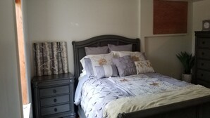 A bedroom with a bed, nightstands, a dresser, and a wall-mounted clock. - Location, Location! Downtown Luxury 1 Bedroom Apt (Ann Arbor)