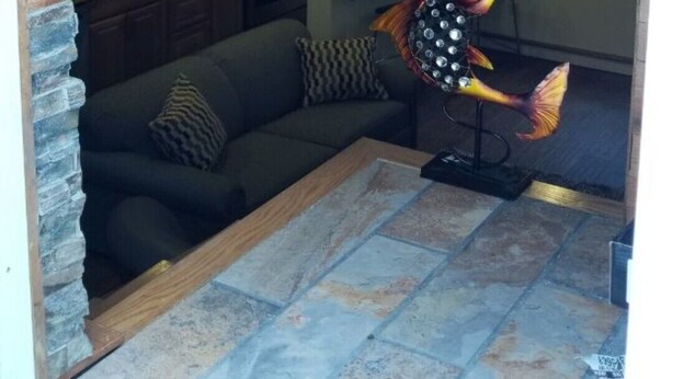 A cozy room with a wooden ceiling, a stone fireplace, a sofa, and a decorative fish lamp. - Location, Location! Downtown Luxury 1 Bedroom Apt (Ann Arbor)