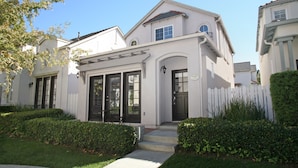 A two-story house with a white exterior, black front doors, and a white picket fence.