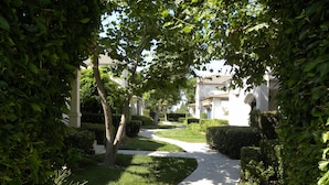 A pathway leading to a building with a white facade and arched windows.