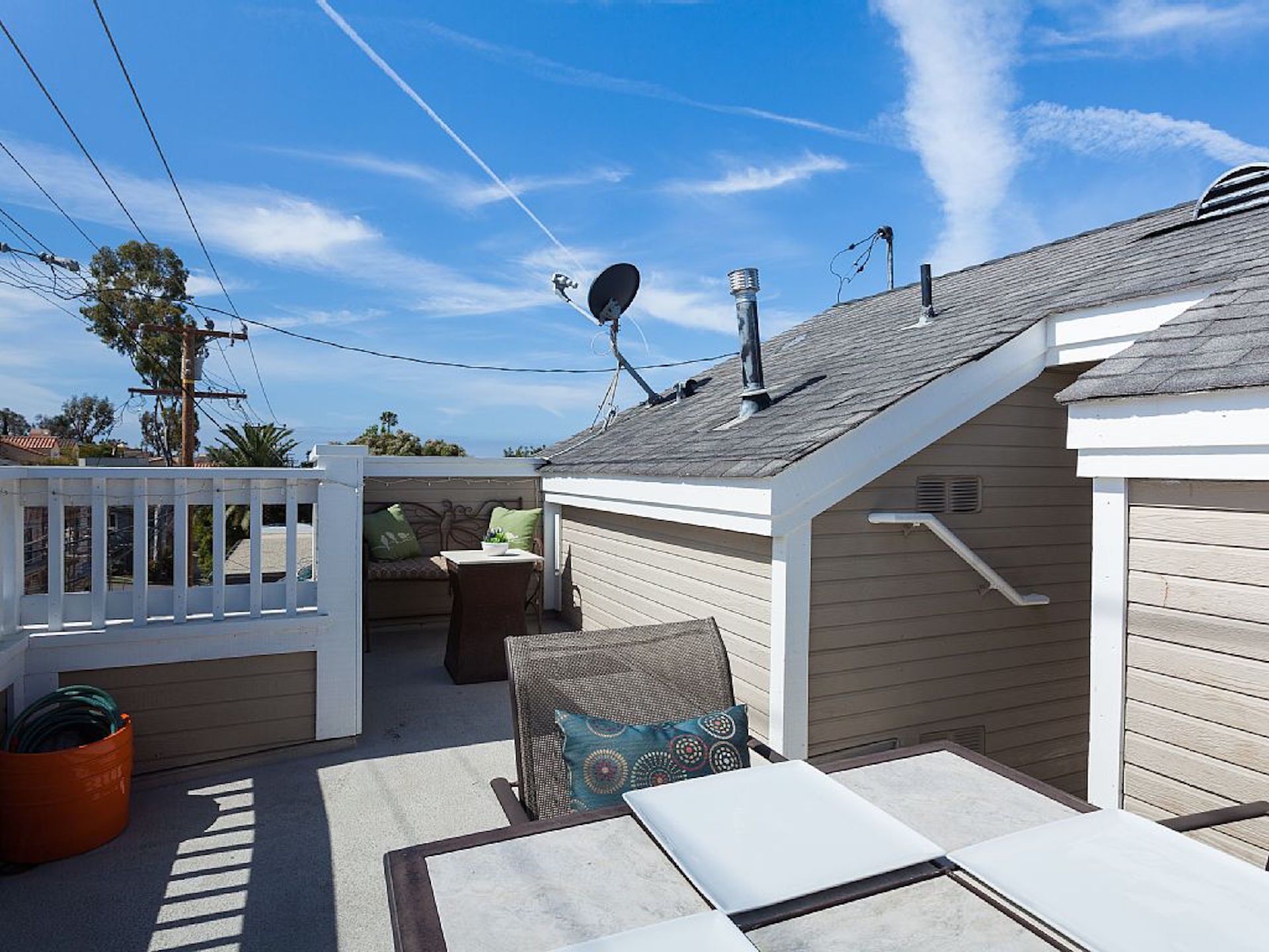 Un área de patio techada al aire libre con cerca blanca, una mesa y una silla.