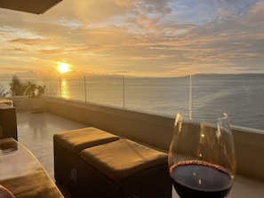 Enjoy a tranquil ocean view from this serene balcony, complete with wicker furniture and a potted plant.