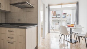 A modern kitchen with a built-in stove, wooden cabinets, and a view to a balcony with a dining area. - Nice apartment one minute from the beach (Playa de San Juan)