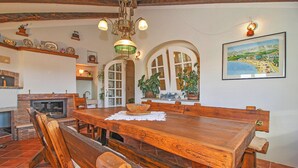 Un coin repas avec une table et des bancs en bois, une cheminée et un tableau au mur.