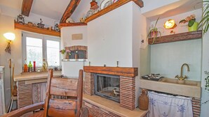 A rustic kitchen with a wooden chair, a brick fireplace, and a window overlooking a garden. - Leandra in Rovinjsko Selo - Istrien / Leandra in Rovinjsko Selo - Appartement für 2 Personen ST1 (Rovinj)