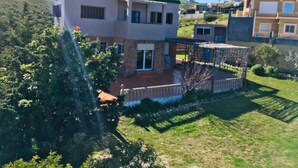 Een huis met twee verdiepingen, een balkon, een overdekte patio en een omheinde tuin.