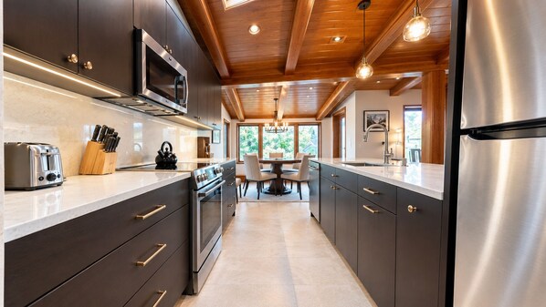 Una cocina moderna con armarios oscuros, electrodomésticos de acero inoxidable y una isla central.