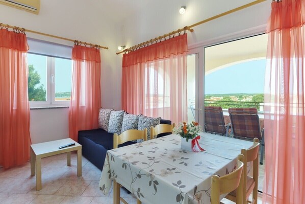 A dining area with a table set for four, a sofa, and a view of the outdoors.