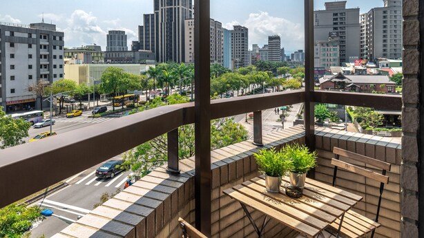 Uma varanda com vista para a paisagem urbana, com edifícios modernos e céu claro.