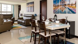 Uma sala de estar moderna com área de jantar, apresentando um sofá, uma mesa de jantar com cadeiras e obras de arte nas paredes.