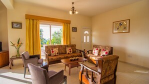 A living room with a sofa, armchairs, a coffee table, and a TV. - Corallia Villa ,3 Bedrooms see and Forest View (Ayia Marina Chrysochous)